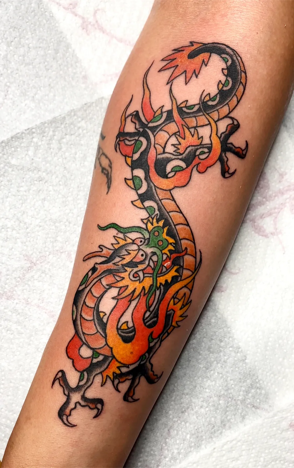 Tatuaje de dragón tradicional japonés a color en antebrazo — líneas sólidas y sombreado, Valencia